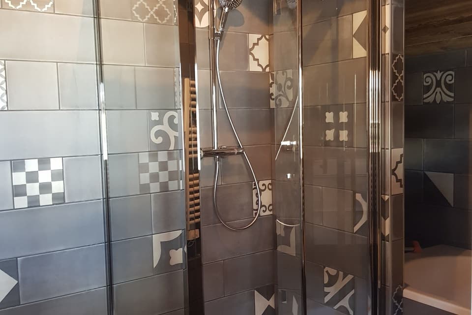 Cabine de douche vitrée avec colonne de douche et faïence façon carreaux de ciment, installée par KAT Plomberie