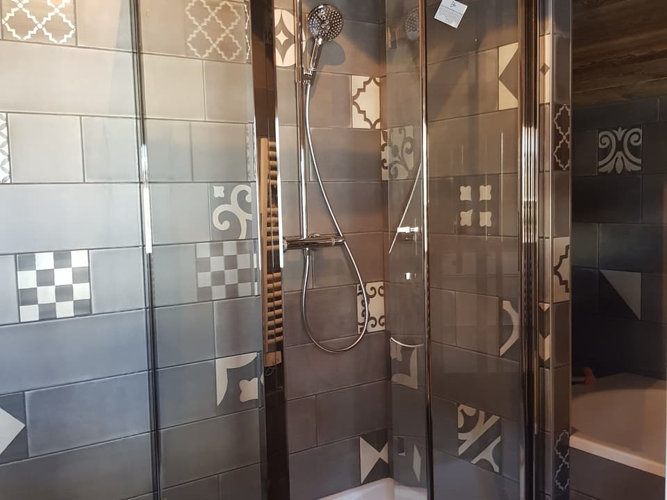 Cabine de douche vitrée avec colonne de douche et faïence façon carreaux de ciment, installée par KAT Plomberie