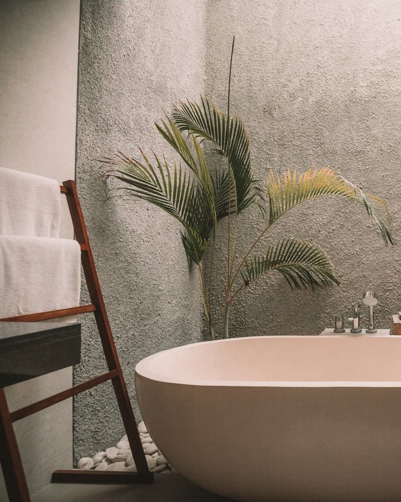 Salle de bain contemporaine avec baignoire îlot, murs en enduit minéral et galets